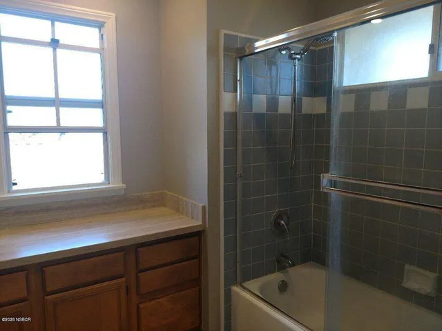 a bathroom with a tub a sink a window and a shower