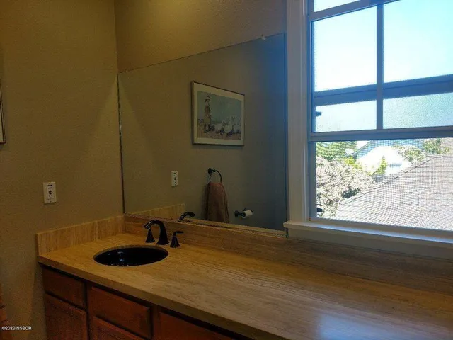 a bathroom with a granite countertop sink and a large mirror next to a window