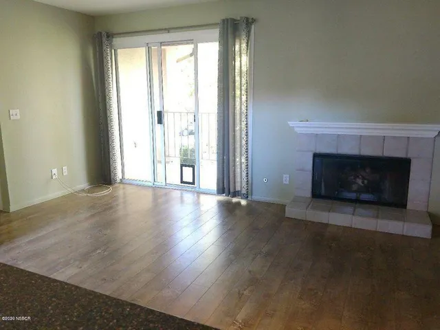 an empty room with wooden floor fireplace and windows