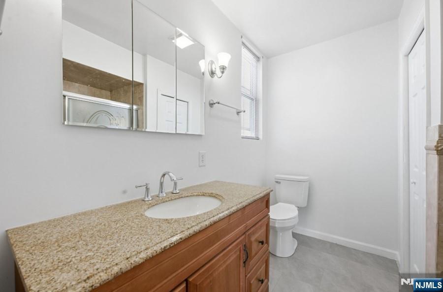 693 North 8th Street Newark, NJ 07107 - Photo 5 of 23 a bathroom with a granite countertop sink a toilet and mirror