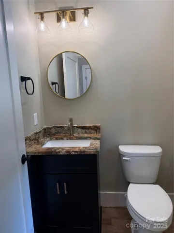 a bathroom with a granite countertop toilet sink and mirror