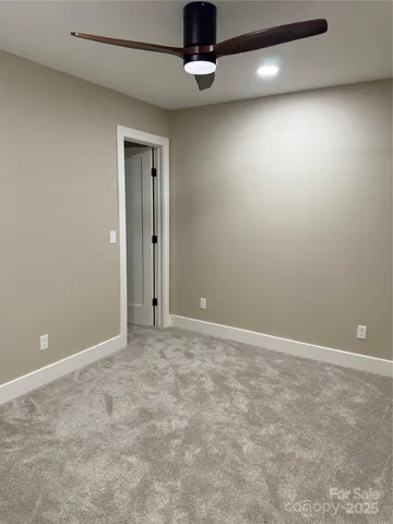 an empty room with a chandelier fan and windows