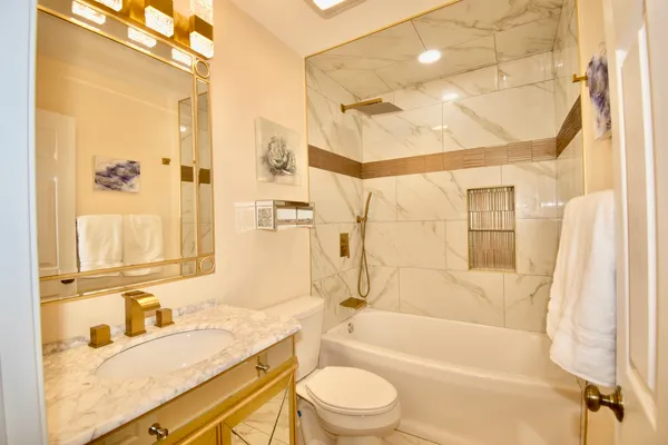a bathroom with a granite countertop sink a toilet and shower