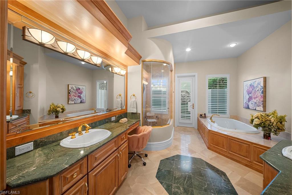 10057 Orchid Ridge Lane Estero, FL 34135 - Photo 17 of 30 a spacious bathroom with a granite countertop tub a double vanity sink and a large mirror