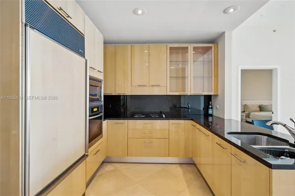 a kitchen with stainless steel appliances granite countertop a stove a sink and a granite counter tops with white cabinets