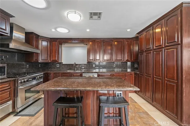 a kitchen with granite countertop a stove a sink and a refrigerator