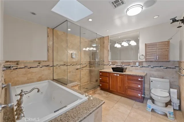 a large bathroom with a granite countertop sink a toilet a mirror and bathtub