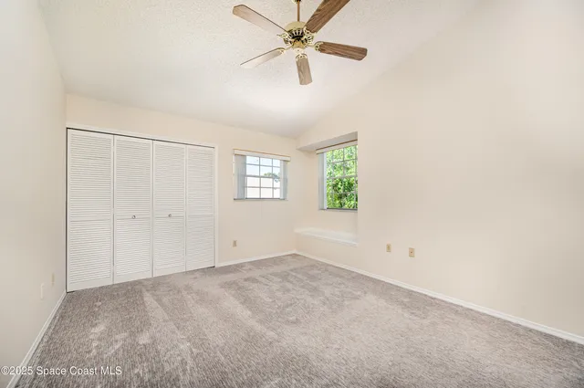 an empty room with windows and fan