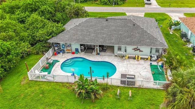 an aerial view of a house with a yard and trees all around
