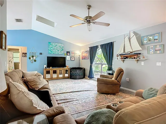 a living room with furniture a flat screen tv and a large window