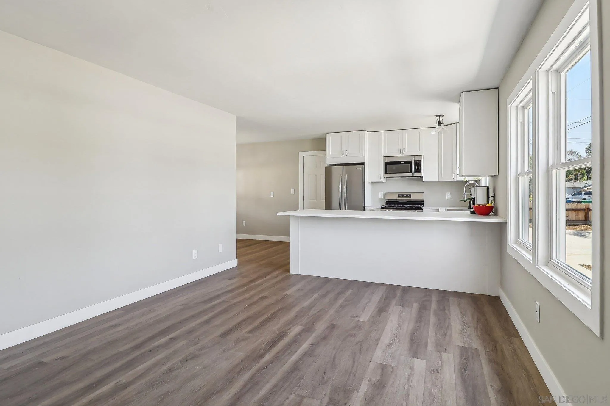 9055 Gorge Avenue Santee, CA 92071 - Photo 11 of 28 a large white kitchen with kitchen island a sink wooden floor and white stainless steel appliances