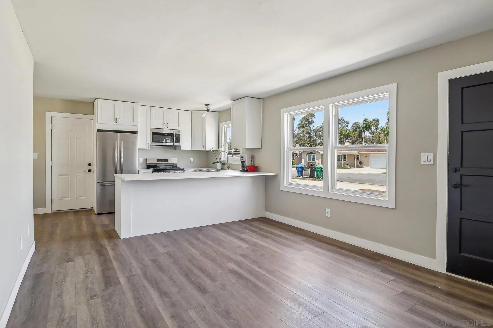 9055 Gorge Avenue Santee, CA 92071 - Photo 7 of 28 a kitchen with stainless steel appliances granite countertop a stove a sink dishwasher a refrigerator with white cabinets and wooden floor