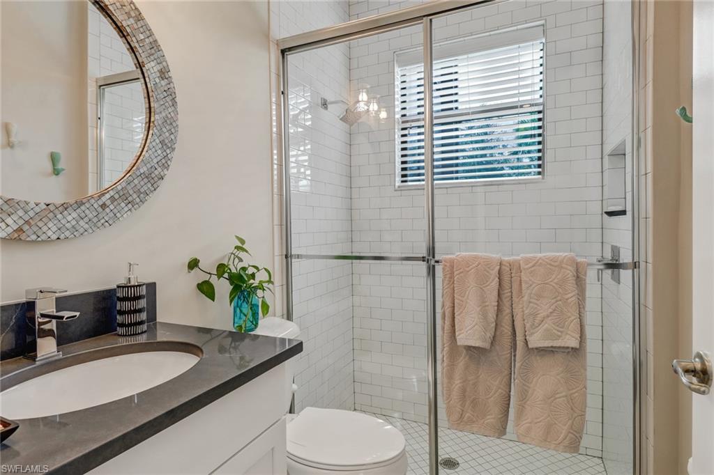 4663 Azalea Drive Naples, FL 34119 - Photo 15 of 34 a bathroom with a granite countertop sink a toilet a mirror and shower