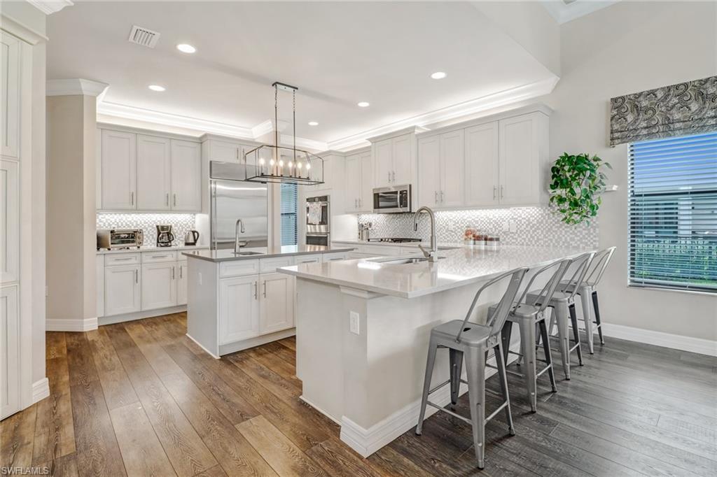 4663 Azalea Drive Naples, FL 34119 - Photo 10 of 34 a kitchen with kitchen island white cabinets and wooden floor