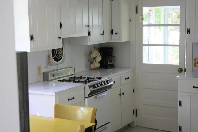 a kitchen with stainless steel appliances granite countertop white cabinets and a stove