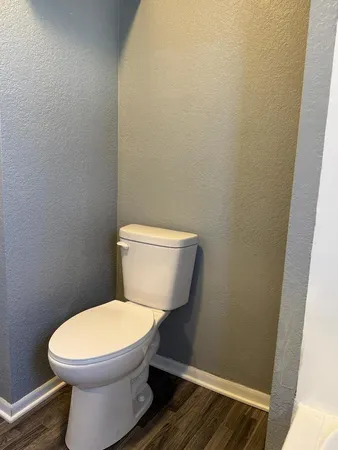 a white toilet sitting next to a wooden cabinet