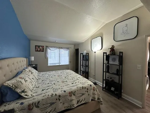 a bedroom with a bed and a lamp on dresser