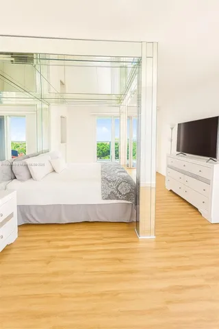 a spacious bedroom with a bed and a flat screen tv