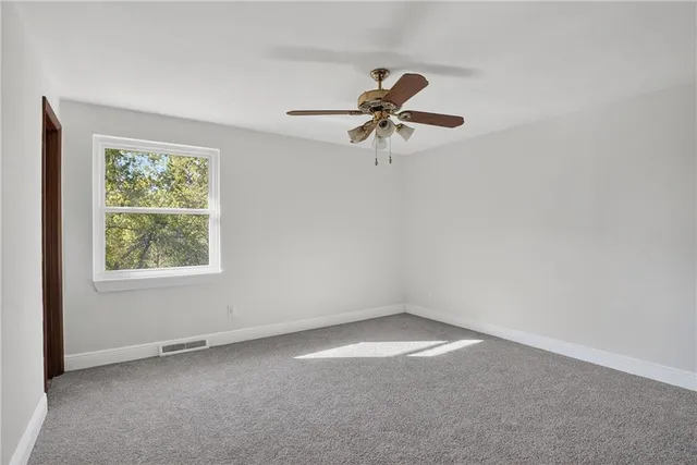 an empty room with a window and a fan