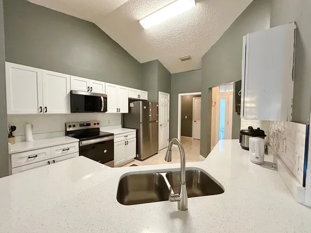 a kitchen with stainless steel appliances a sink dishwasher a refrigerator and a stove with wooden floor