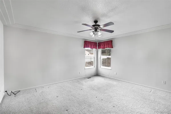an empty room with windows and fan