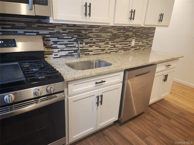 a kitchen with granite countertop a stove and white cabinets