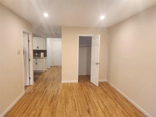 a view of a hallway with wooden floor and a kitchen space