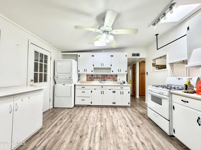 a kitchen with stainless steel appliances a stove refrigerator sink cabinets and wooden floor