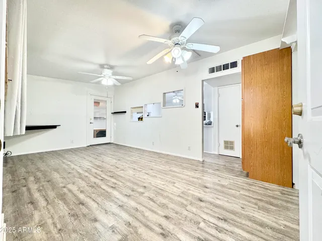 a view of a livingroom with a chandelier fan and kitchen view