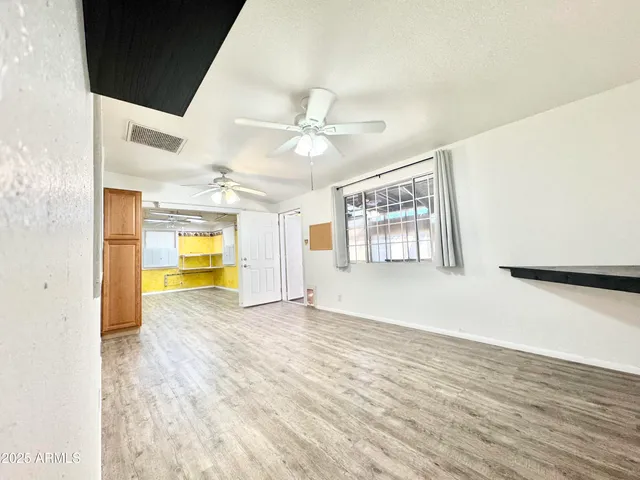 a view of an empty room with a window and wooden floor