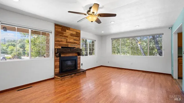 a view of an empty room with a window and wooden floor