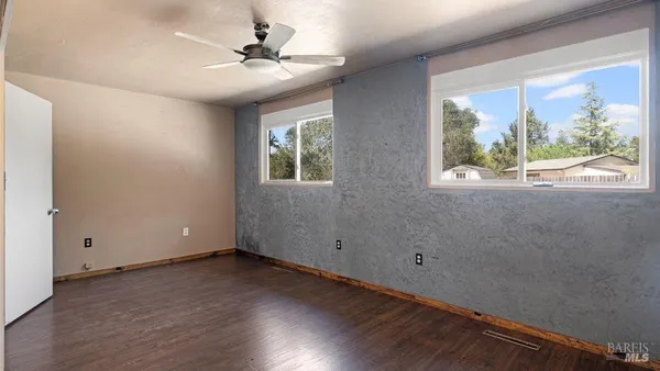 a view of an empty room with a window and wooden floor