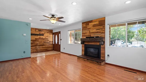 an empty room with windows fireplace and a ceiling fan