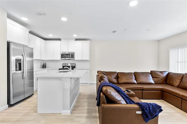 a living room with stainless steel appliances furniture and a couch