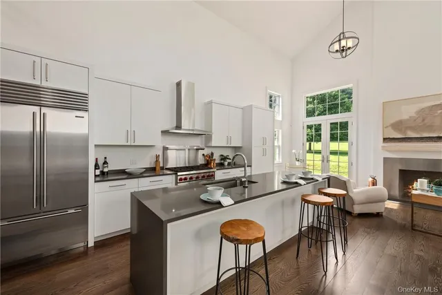 a kitchen with stainless steel appliances granite countertop a stove a refrigerator a kitchen island a stove and white cabinets