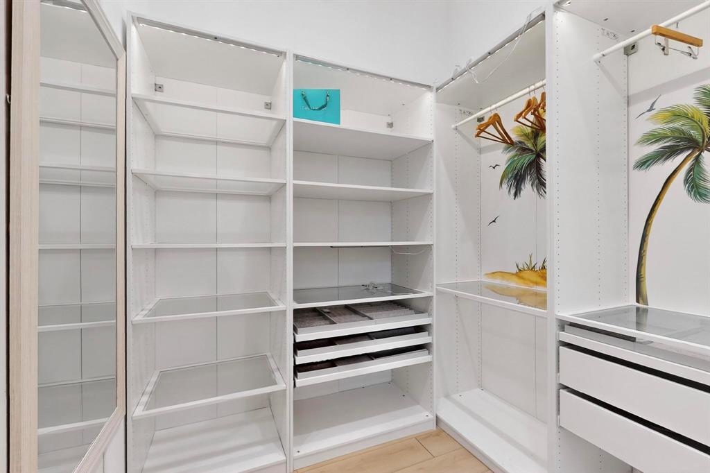 3946 North Cresthaven Road Dallas, TX 75209 - Photo 18 of 38 Custom closet system featuring white shelving, integrated drawers, hanging rods, and a full-length mirror