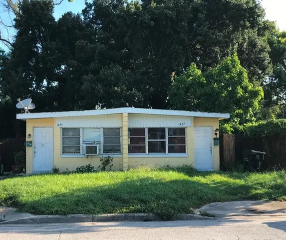front view of a house with a yard and potted plants