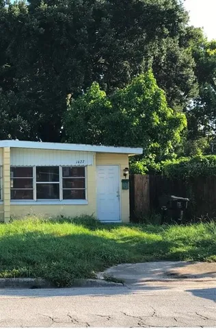 a view of a house with a yard and a large tree