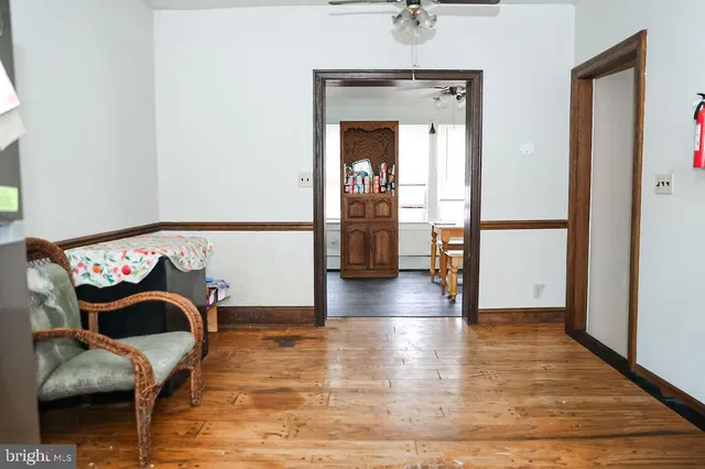 a view of a hallway with wooden floor and a small white wall