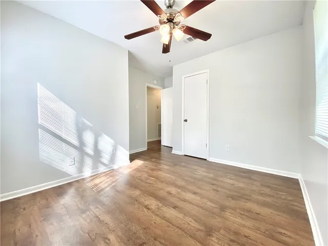 a view of empty room with wooden floor and fan