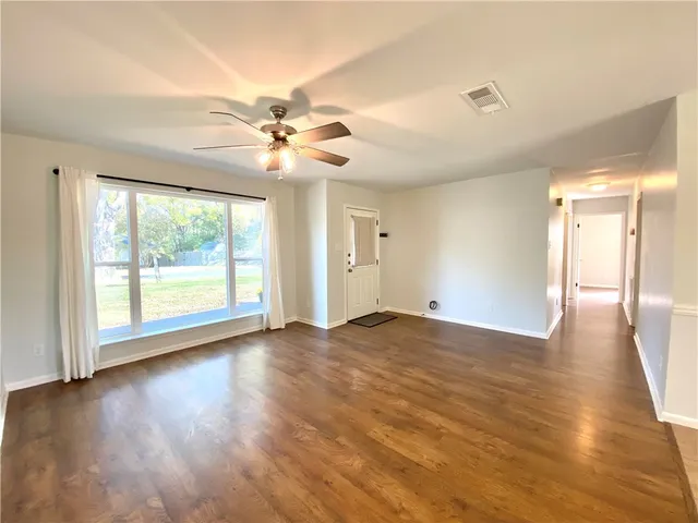 a view of an empty room with window and wooden floor