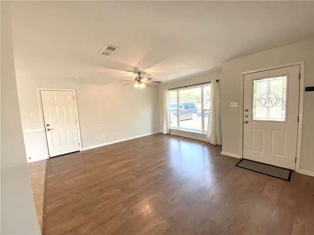 an empty room with wooden floor and windows