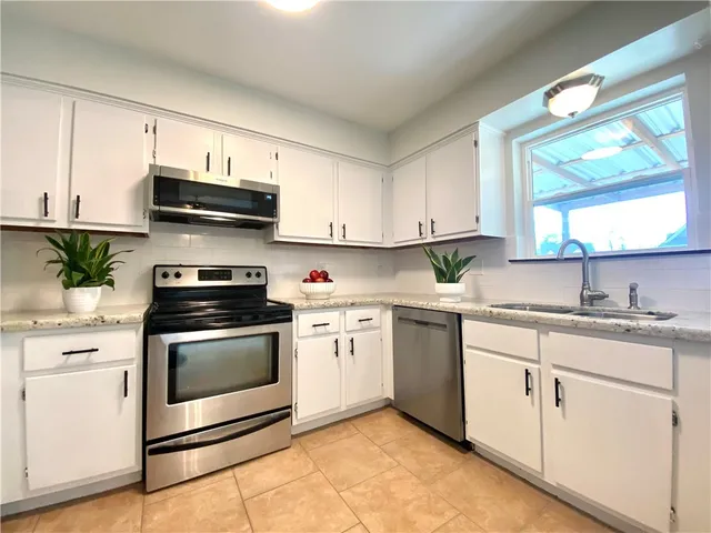 a kitchen with granite countertop white cabinets white stainless steel appliances and a sink