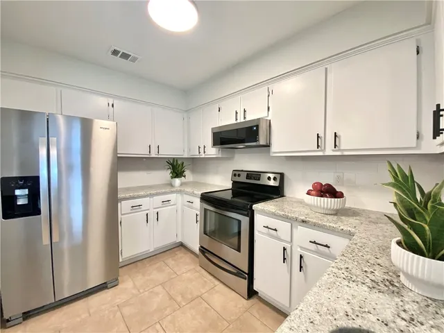 a kitchen with stainless steel appliances granite countertop a refrigerator sink and white cabinets