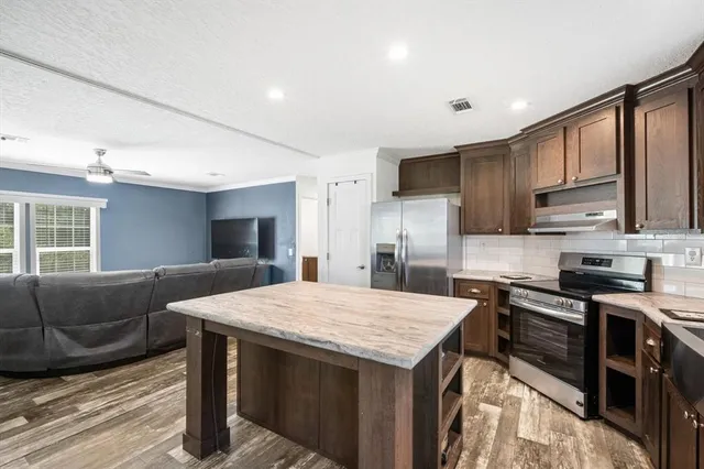 a kitchen with kitchen island a sink stove top oven and refrigerator