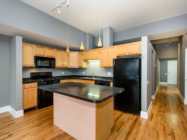 a kitchen with granite countertop a refrigerator and a stove top oven