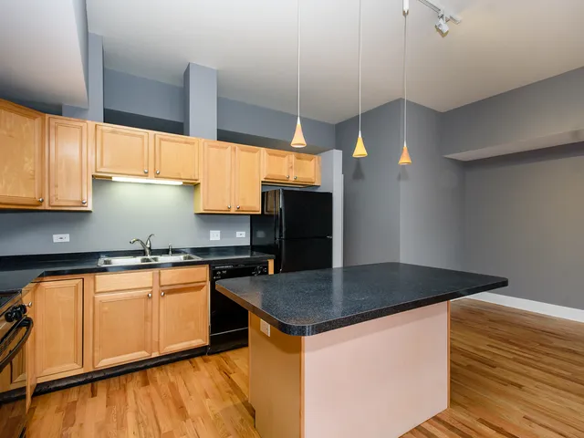 a kitchen with granite countertop a sink a counter top space cabinets and stainless steel appliances