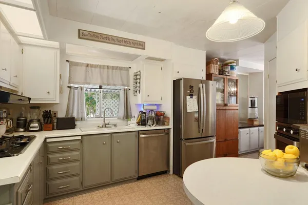 a kitchen with stainless steel appliances a sink a stove a refrigerator cabinets and a window