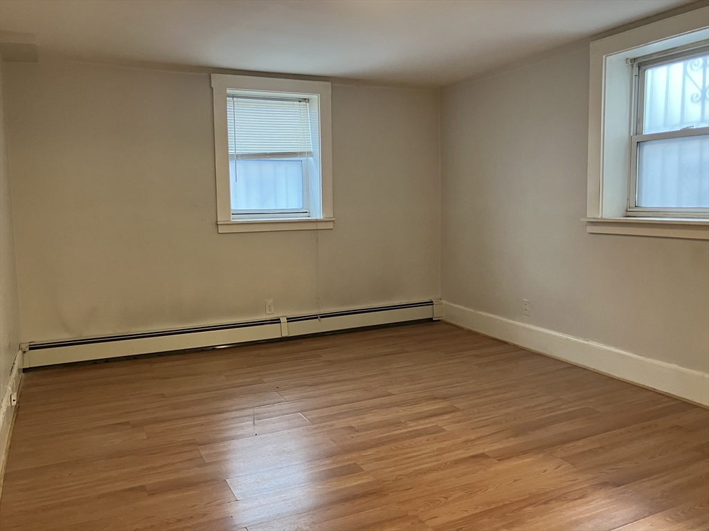211 St Paul Street, Unit B Brookline, MA 02446 - Photo 5 of 6 a view of an empty room with wooden floor and a window