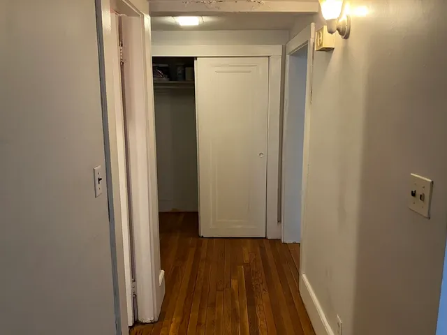 a view of a hallway with wooden floor and closet